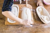 Panaderos manos haciendo diseño en la masa - foto de stock