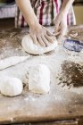 Panaderos manos amasar la masa en la mesa - foto de stock