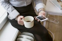 Деловая женщина с мобильным телефоном и кофейной чашкой — стоковое фото