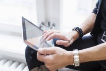 Бізнес-леді, використовуючи планшет і сидячи на підвіконні — стокове фото