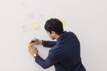 Businessman writing reminders on adhesive note — Stock Photo