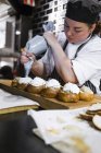 Femme chef glaçage petits pains dans la cuisine — Photo de stock