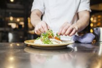 Шеф-кухар прикрашає їжу в тарілці — стокове фото