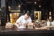Young chef writing recipe — Stock Photo