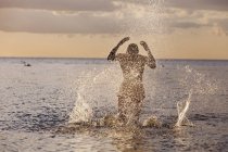 Homem feliz correndo e salpicando água — Fotografia de Stock