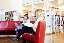 Молоді жінки сидять на дивані в бібліотеці — стокове фото