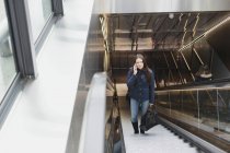 Mulher usando telefone celular na escada rolante — Fotografia de Stock