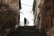Человек с велосипедом движется вверх по ступеням — стоковое фото