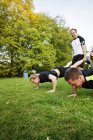 Pessoas que se exercitam no campo gramado — Fotografia de Stock