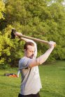 Young man lifting hammer in park — Stock Photo