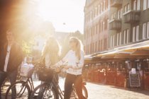 Amis avec des vélos marchant dans la rue — Photo de stock