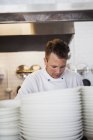 Chef with stack of plates — Stock Photo