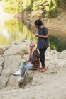 Female friends on rock by lake — Stock Photo