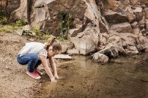Дівчина миє руки на озері — стокове фото