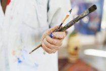 Female artist holding paintbrushes — Stock Photo
