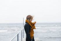 Frau mit Schal steht auf Seebrücke — Stockfoto