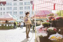 Mujer madura comprando flores - foto de stock