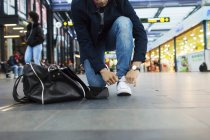Чоловік зав'язує шнурки на залізничній станції — стокове фото