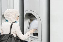Mujer usando la máquina de billetes - foto de stock
