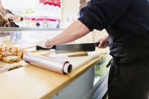 Shopkeeper chopping cheese — Stock Photo