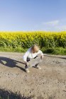 Junge bereitet sich auf Skateboard auf Feldweg vor — Stockfoto