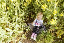 Mädchen sitzt inmitten von Pflanzen — Stockfoto