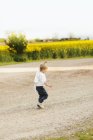 Грайливий хлопчик ходить по брудній дорозі — стокове фото