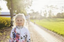 Smiling girl standing on dirt road — Stock Photo