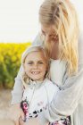 Happy girl standing with loving mother — Stock Photo