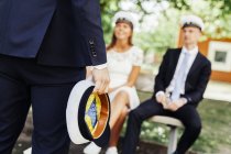 Graduate holding cap while friends sitting — Stock Photo