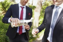 Masculino graduado derramando champanhe — Fotografia de Stock