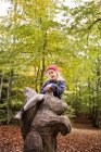 Menina feliz sentado em escultura de madeira — Fotografia de Stock