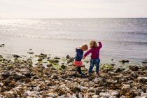 Dos chicas de pie en la playa - foto de stock