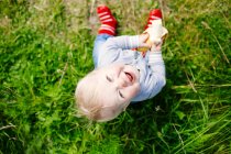 Happy boy sitting on grassy field — Stock Photo