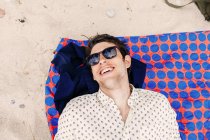 Man in sunglasses laying at beach — Stock Photo