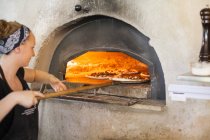 Шеф-кухар кладе піцу в духовку — стокове фото