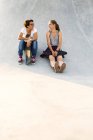 Друзья со скейтбордами сидят в скейт-парке — стоковое фото
