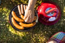Hand taking barbecue grill sausage — Stock Photo
