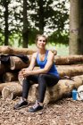 Mulher sentada em tronco de madeira — Fotografia de Stock