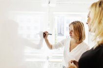 Wniversity students discussing by whiteboard — Stock Photo