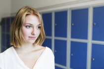 Young woman standing by locker — Stock Photo