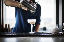 Bartender pouring cocktail in glass — Stock Photo