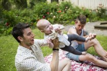 Gay pareja jugando con bebé chica - foto de stock