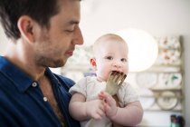 Father looking at baby biting fork — Stock Photo