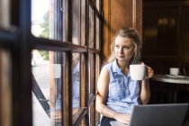 Женщина смотрит через окно в кафе — стоковое фото
