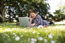 Счастливая женщина с ноутбуком в парке — стоковое фото