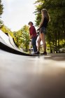 Mädchen halten Skateboard und stehen auf Rampe — Stockfoto