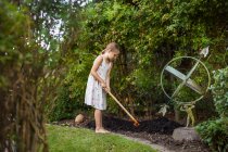 Ragazza che diffonde fertilizzante con forchetta da giardino — Foto stock