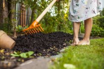 Girl spreading fertilizer with gardening fork — Stock Photo