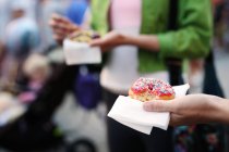 Mulher segurando donut na rua — Fotografia de Stock